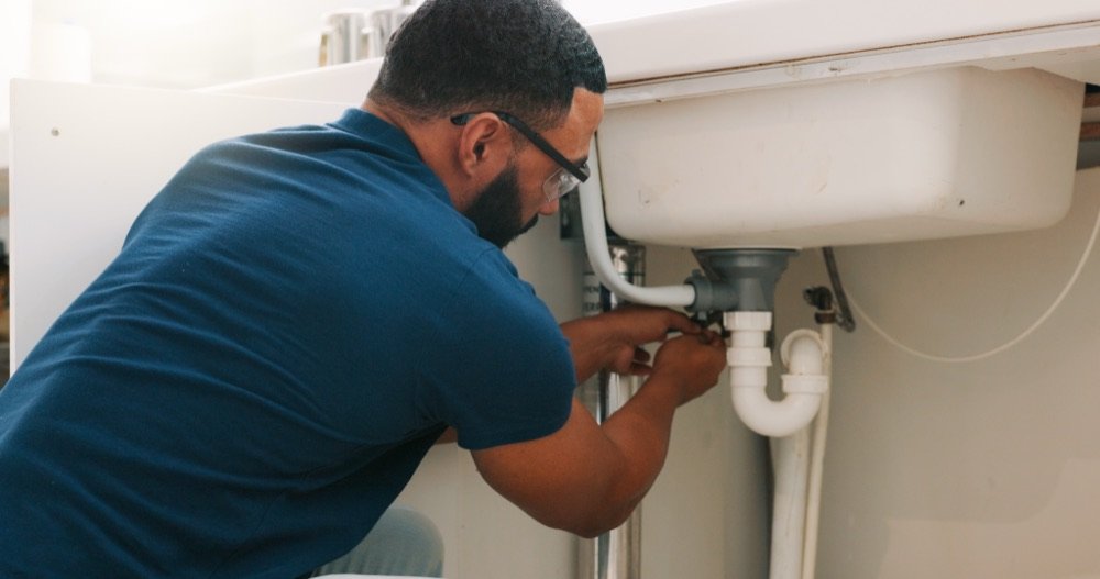Plumber working under a sink